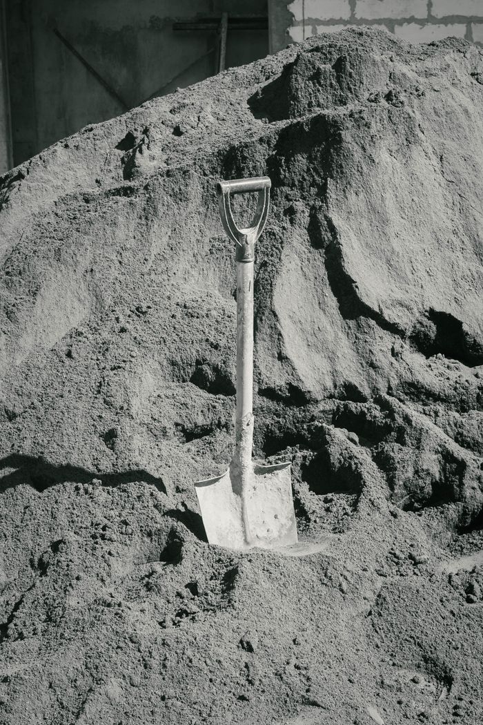 Crafting Captivating Headlines: Your awesome post title goes here A solitary shovel upright in a massive sand pile, representing construction and labor.